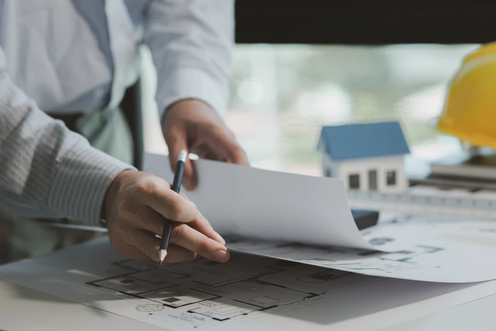 Scène d'intérieur professionnel avec personne en chemise blanche signant des documents immobiliers