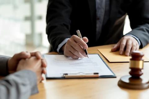Scène d'affaires en intérieur avec poignée de main entre deux personnes en costume au-dessus d'une table de réunion